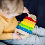 toddler playing wooden xylophone toy